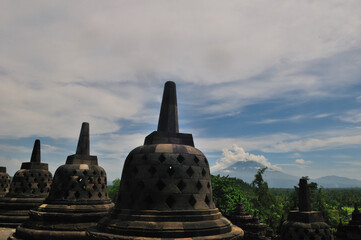 Few of old Stupas of Borobudur Temple with background Mount Merapi in Central Java, Indonesia. 