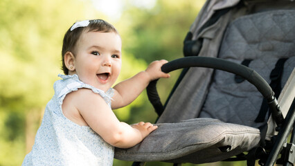 Happy baby in stroller with smiling mother walking in sunny park