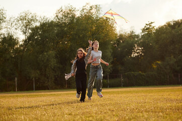 Fototapeta premium Two girls kids are playing with kite on the field