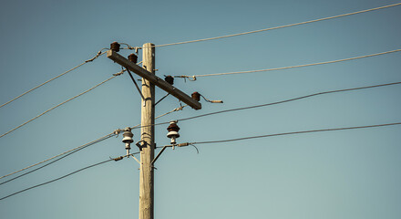 An aged wooden utility pole against a serene blue sky backdrop outdoors
