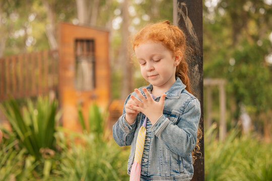 Outdoor portrait of preschool age girl counting fingers on her hand at kindergarten