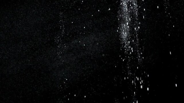 Many dust particles white powder falling from above, floating on empty black contrast background. Slow motion.