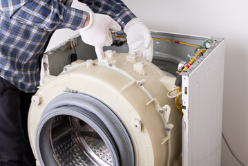Assembling the washing machine, working with the casing. Hands in white gloves work with the internal components of a washing machine, the assembly process after repair