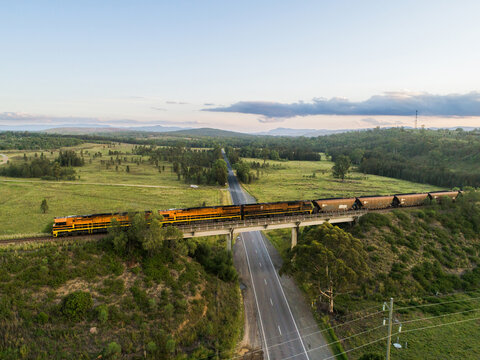 Coal train engine crossing over railway bridge over rural road at dusk
