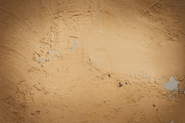 Textured beige wall with subtle imperfections and scratches. The surface appears weathered and rough, showcasing a natural earthy tone.