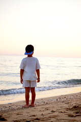 Young child, teenager with fancy clothes and hat on the beach at sunset