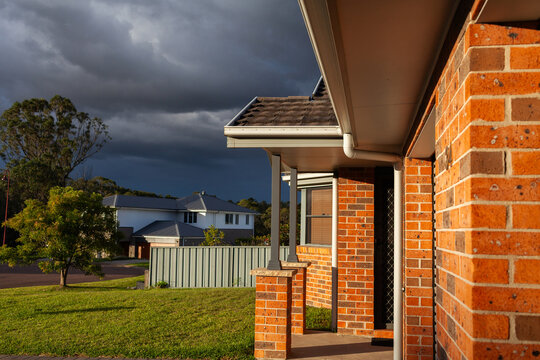 Brick duplex in sunset light with incoming storm clouds in sky