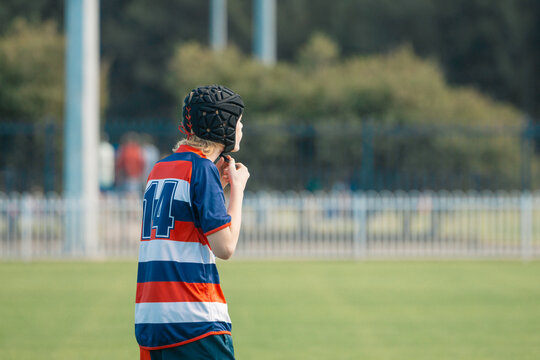Junior rugby union player on field fastening protective head gear