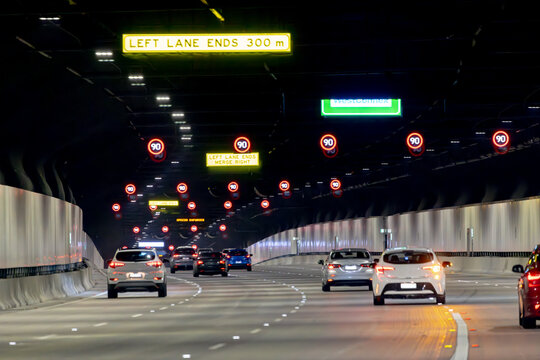 View from a car, Sydney toll road tunnel showing speed signs and four lanes with camera shake