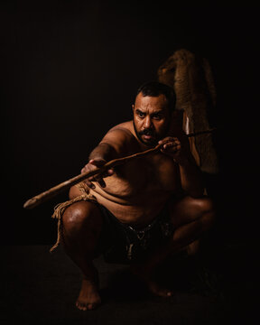 Aboriginal male crouching down aiming spear