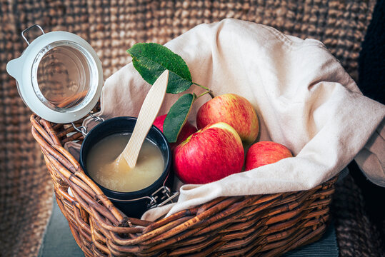A basket of apples and a jar of applesauce with a spoon in it