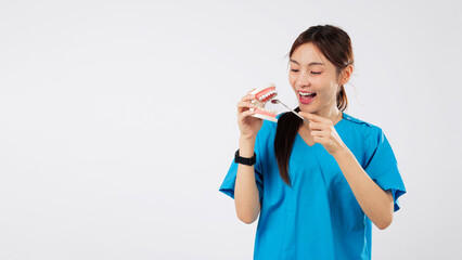 Asian woman smiling, dental model holding mirror, showing teeth in clinic, medical nurse displays oral tool, this dental demonstration ensures healthy gums and teeth, isolated studio white background