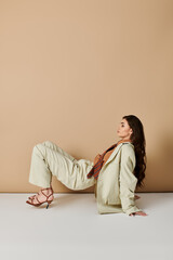 Elegant young woman in fashionable suit poses stylishly in modern studio setting