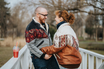 A cheerful couple stands on a bridge, sharing a delightful moment with warm smiles during a calm,...