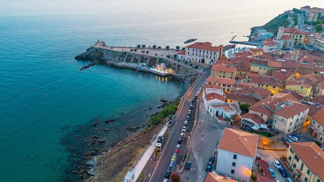 Aerial view of a Mediterranean coastal town with seawall and turquoise bay at dusk