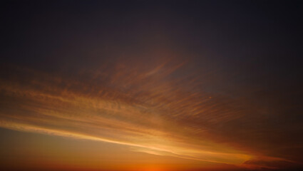 Dramatic sunset sky with wispy clouds illuminated by golden light
