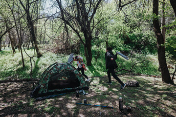 An individual tending to camping gear in a lush forest setting, ideal for outdoor adventure and...