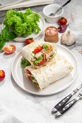 Appetizing Shawarma with chicken and fresh vegetables on a light background