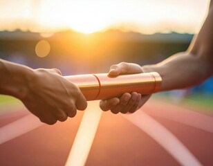 Two athletes exchange a baton during a relay race at sunset, symbolizing teamwork and collaboration.	