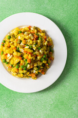 Colorful salad includes boiled egg, chicken breast, diced potatoes, carrots, and green peas mixed together and drizzled with olive oil, perfect for a healthy meal