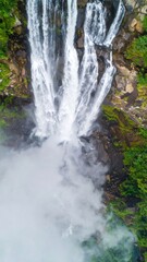 Overhead View of Tropical Waterfalls Surrounded by Lush Green Forest and Mist