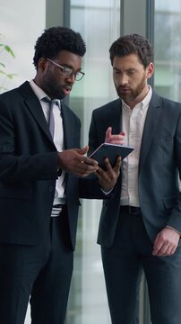 Two multiracial businessmen discussing project in modern office looking at digital tablet together multiethnic business men diverse male colleagues talking cooperation teamwork strategy planning work