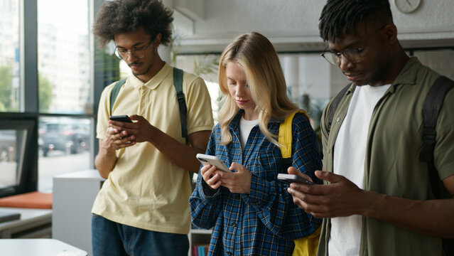 Multiracial group students multiethnic friends African American men guys Caucasian woman girl studying education high school university gadget addict using mobile phones play video game social media