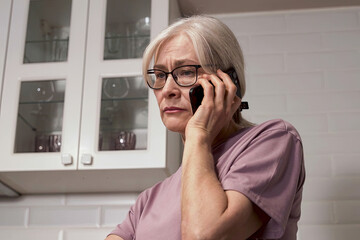 A Concerned Senior Woman on the Phone Portraying Emotion and Connectivity in a Modern Kitchen Environment