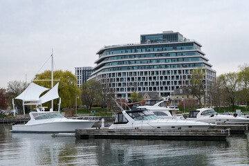 Luxury yachts in the harbor of the wealthiest town in Ontario by the park with new buildings behind
