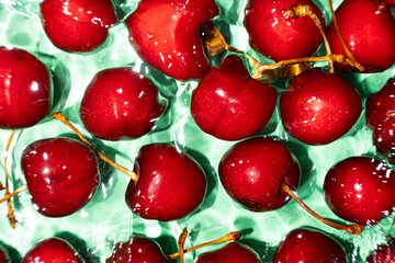 Ripe red sweet cherry in water close-up top view.