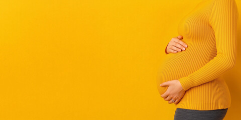Pregnant Woman Holding Belly on Bright Yellow Background with Copy Space