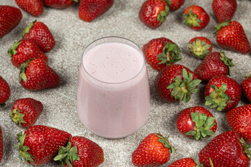 Strawberry sweet milkshake in a glass among fresh ripe strawberries.