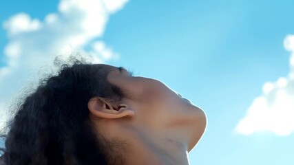 Young woman with curly hair gazing skyward. Ideal for inspiration and personal development content creation.