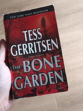 Hand Holding "The Bone Garden" by Tess Gerritsen (New York Times Bestseller