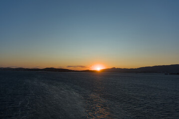 The setting sun creates a vibrant orange glow on the horizon, casting a soft light over the calm...