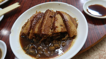 close up of Cantonese dish soy sauce Braised Pork Belly With Preserved Mustard Greens vegetables on a white plate