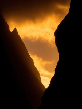 Golden sunset silhouettes mountains in a canyon.