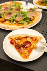 Italian delicious pizza with prosciutto and salami pepperoni on a table in a restaurant or cafe