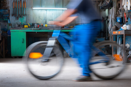 A person riding a bicycle through a workshop with blurred motion to emphasize speed and movement
