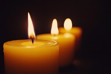 A row of votive candles lit against a dark background, evoking spiritual or ceremonial themes. Suitable for religious ceremonies, meditation, or holiday celebrations.