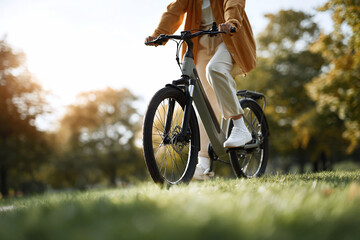 An individual enjoys a leisurely bike ride on a modern ebike through a sundappled park. Illustrates ecofriendly transportation, active lifestyles, and sustainable urban living.