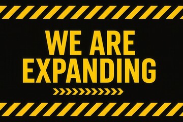 Bold yellow text on a black background reading "WE ARE EXPANDING," surrounded by diagonal yellow caution stripes, conveying a message of growth and development.