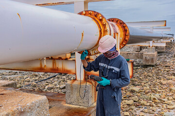 Male worker inspection and measurement thickness of rusted steel pipe, steel deterioration,...