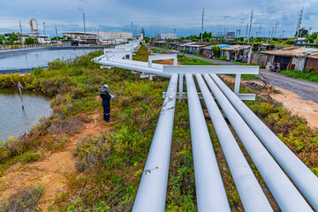 Male worker inspection at steel long pipes and pipe elbows inthe  station oil factory during refinery valve of visual check record pipeline tank oi
