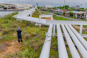 Male worker inspection at steel long pipes and pipe elbows inthe  station oil factory during refinery valve of visual check record pipeline tank oi