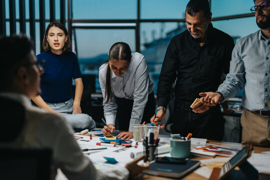 A diverse group of colleagues brainstorms innovative ideas in a dynamic office environment, working together to meet a project deadline late in the evening.