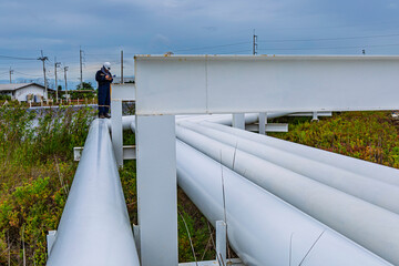 Male worker inspection at steel long pipes and pipe elbows inthe  station oil factory during...