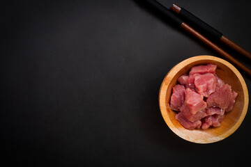 chopsticks and pieces of beef in a wooden bowl with space for text