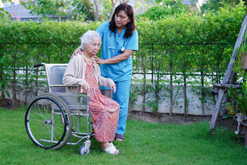Doctor help Asian elderly woman disability patient walk with walker in park, medical concept.