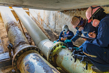 Male worker inspection of rusted steel pipe, underground steel deterioration, widespread corrosion,...